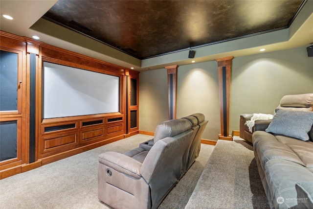 home theater room with a tray ceiling, carpet floors, and decorative columns