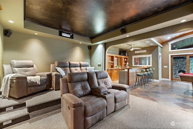 carpeted home theater with a tray ceiling, vaulted ceiling, and ceiling fan