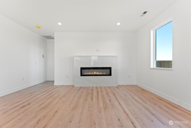 unfurnished living room featuring light hardwood / wood-style floors and a premium fireplace