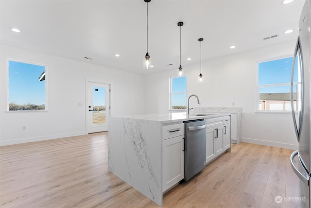 kitchen with appliances with stainless steel finishes, sink, white cabinets, hanging light fixtures, and light hardwood / wood-style floors