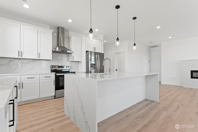 kitchen with stainless steel appliances, white cabinets, and wall chimney exhaust hood