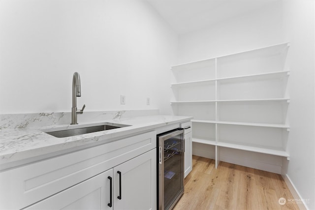 clothes washing area with sink, wine cooler, and light hardwood / wood-style flooring