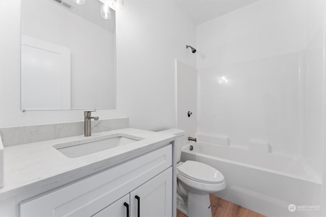 full bathroom featuring vanity, hardwood / wood-style flooring, toilet, and washtub / shower combination