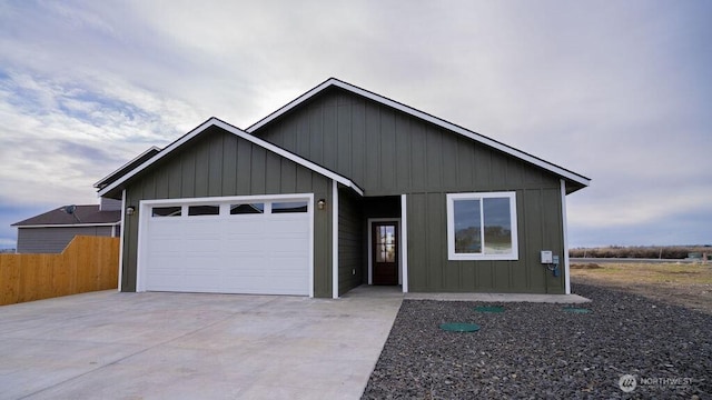 view of front of house featuring board and batten siding, concrete driveway, fence, and a garage