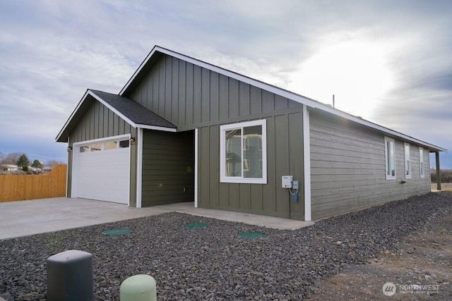 view of front facade featuring a garage, board and batten siding, and fence