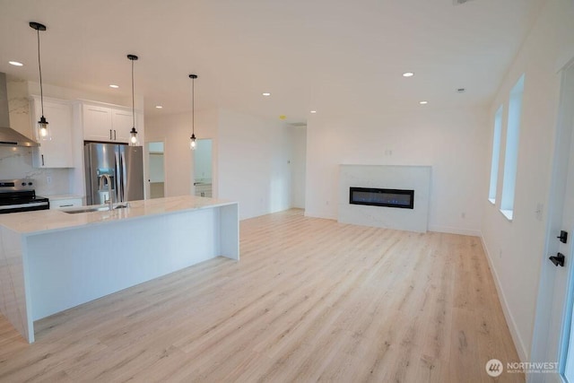 1300 Marina Dr Unit 12, Moses Lake, WA 98837 - kitchen featuring a sink, light wood-style floors, appliances with stainless steel finishes, white cabinets, and wall chimney range hood