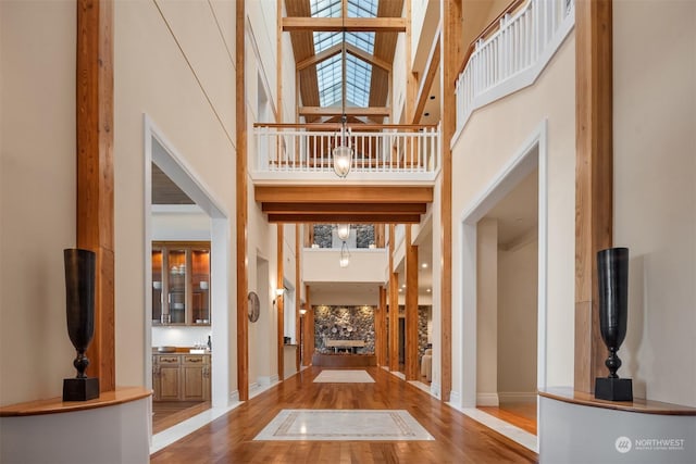 entryway with a towering ceiling, hardwood / wood-style floors, and a skylight