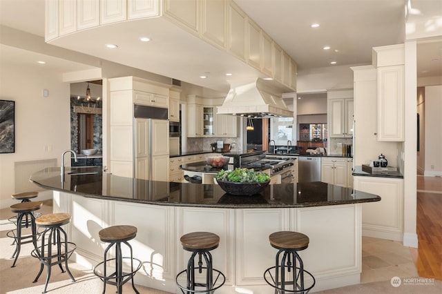 kitchen with a kitchen breakfast bar, stainless steel dishwasher, custom range hood, and white cabinets