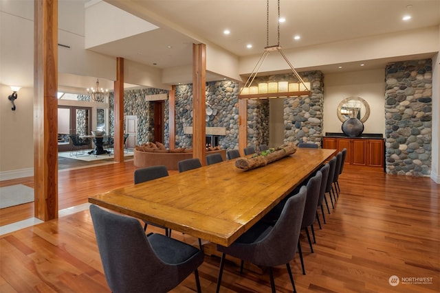 dining space featuring hardwood / wood-style flooring, a chandelier, and decorative columns