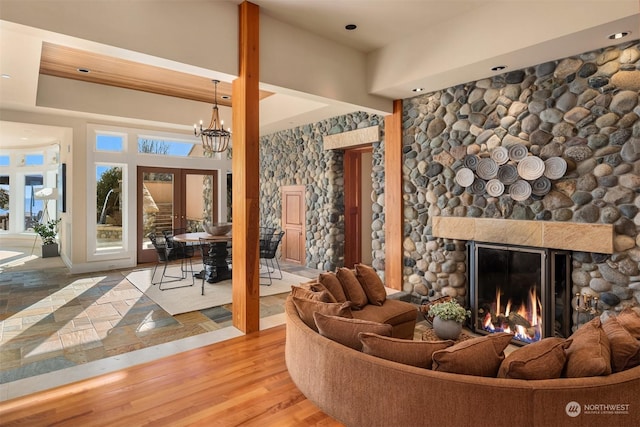 living room with an inviting chandelier, a fireplace, light hardwood / wood-style floors, and french doors