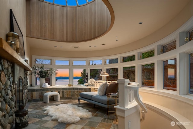 sunroom / solarium with a water view and a stone fireplace