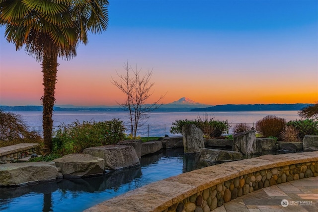 pool at dusk with a water and mountain view