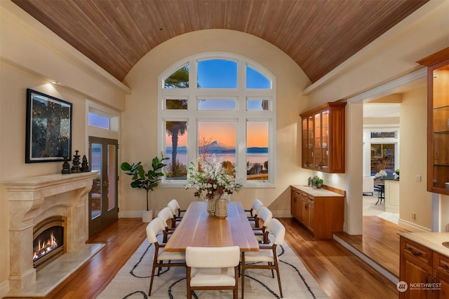 dining space with wood ceiling, lofted ceiling, a fireplace, and light wood-type flooring