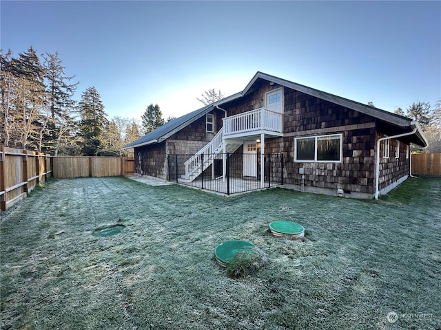 back of house featuring a balcony and a lawn