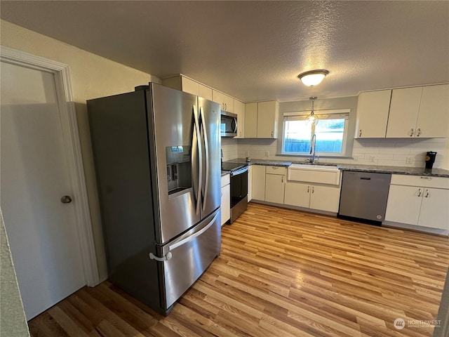 kitchen with sink, appliances with stainless steel finishes, light hardwood / wood-style floors, white cabinets, and decorative backsplash