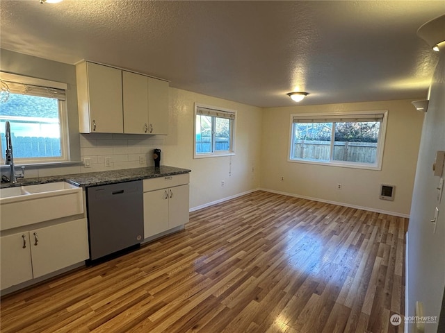 kitchen featuring white cabinets, sink, dark stone countertops, and dishwashing machine