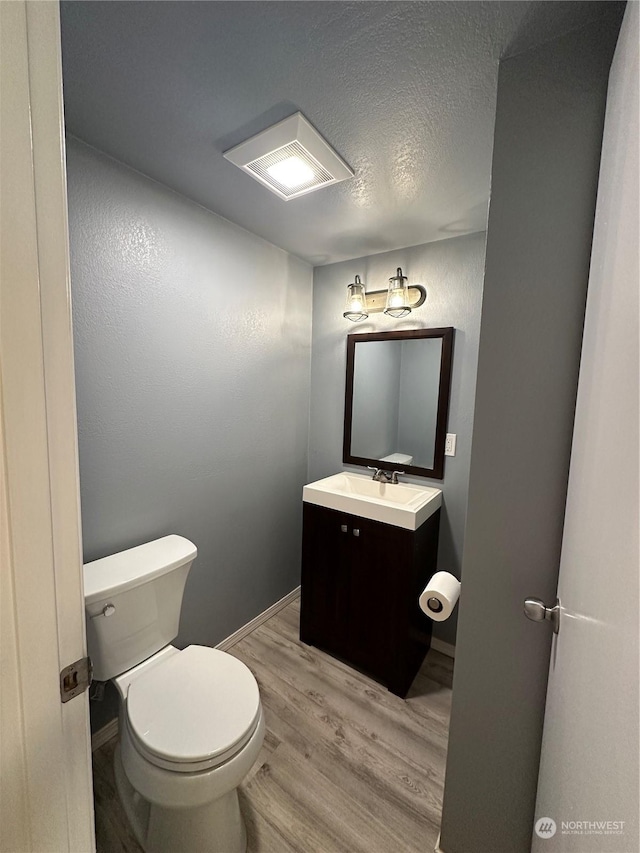 bathroom with wood-type flooring, vanity, a textured ceiling, and toilet