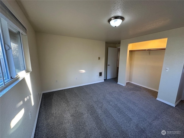 unfurnished bedroom with dark carpet, a closet, and a textured ceiling