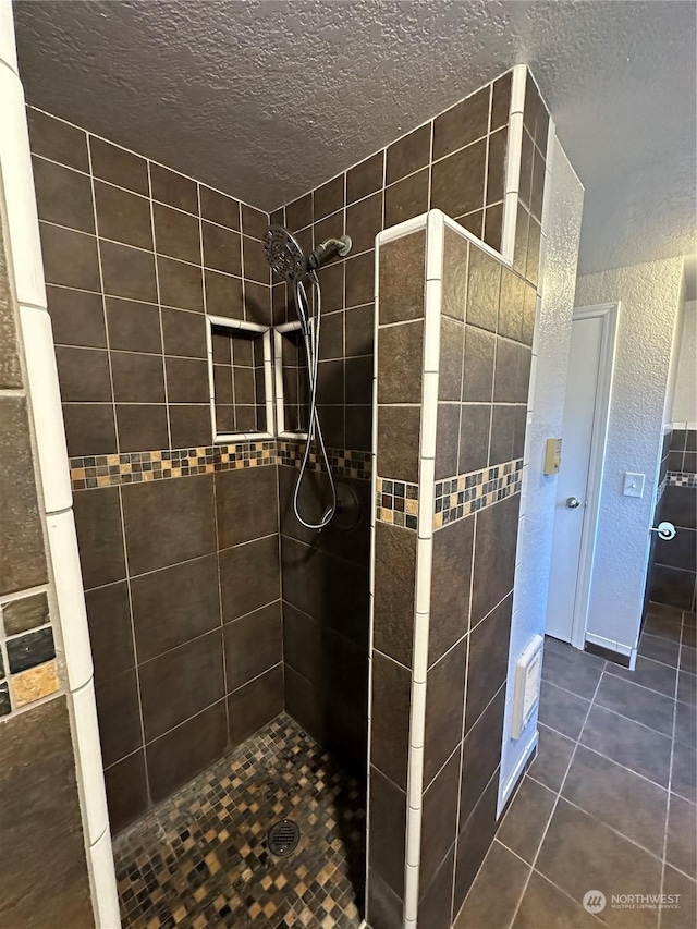 bathroom with a tile shower, tile patterned flooring, and a textured ceiling