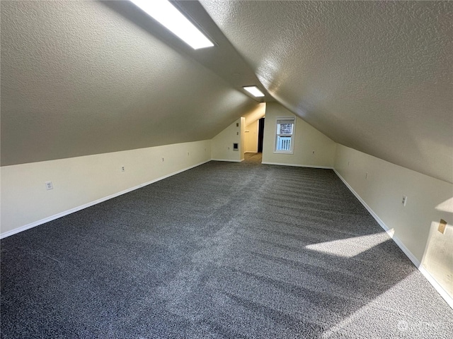 bonus room featuring dark colored carpet, vaulted ceiling, and a textured ceiling