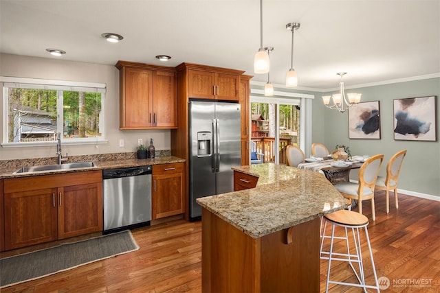 kitchen with a kitchen bar, brown cabinetry, appliances with stainless steel finishes, and a sink