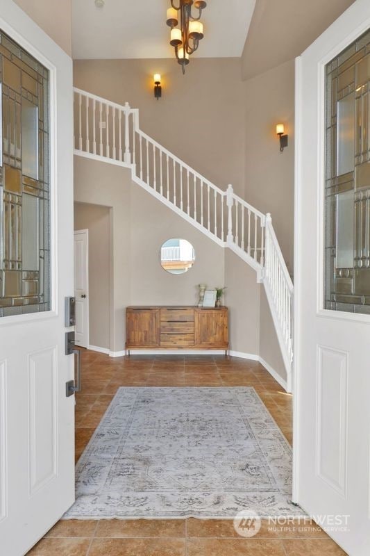 tiled foyer with an inviting chandelier and a high ceiling