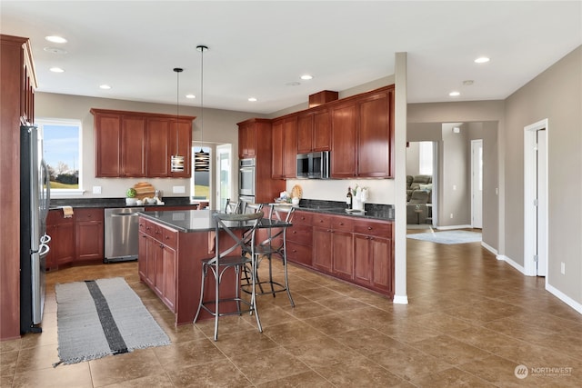 kitchen with a kitchen island, pendant lighting, a kitchen bar, and appliances with stainless steel finishes