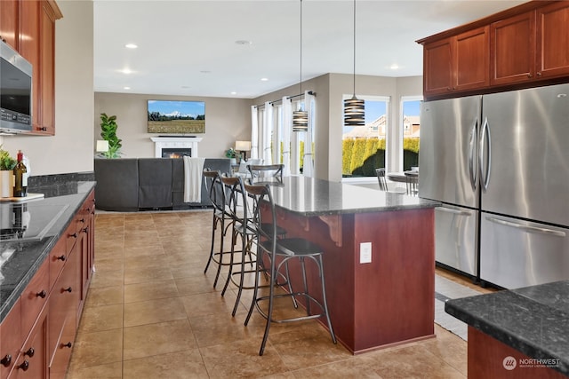 kitchen with light tile patterned floors, a breakfast bar, appliances with stainless steel finishes, a center island, and decorative light fixtures