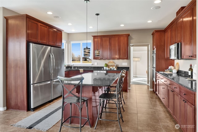 kitchen featuring light tile patterned floors, a breakfast bar, stainless steel appliances, a kitchen island, and decorative light fixtures