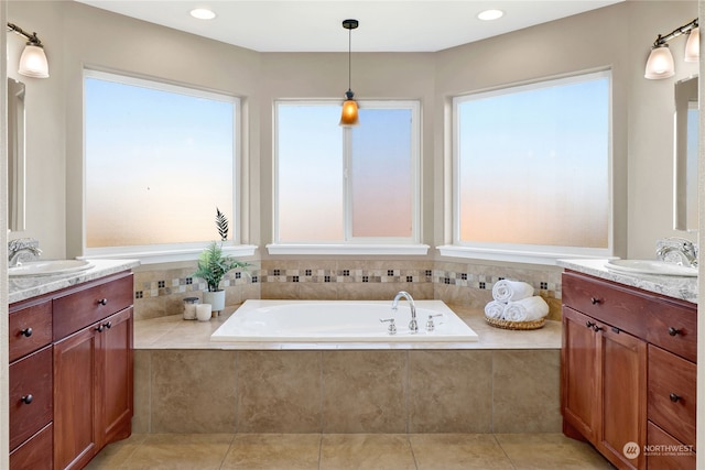 bathroom with vanity, tiled tub, tile patterned flooring, and a healthy amount of sunlight