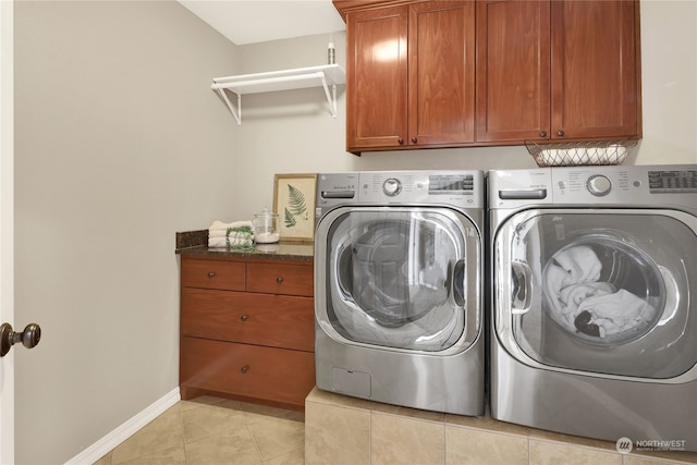 laundry room featuring cabinets, light tile patterned flooring, and washing machine and clothes dryer