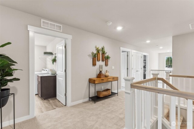 hallway featuring visible vents, baseboards, an upstairs landing, and light carpet