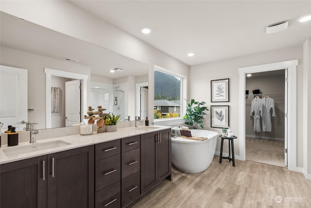 full bathroom featuring double vanity, a freestanding bath, a sink, and a stall shower