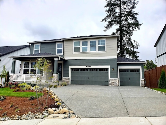 view of front of house with fence, covered porch, driveway, and stone siding