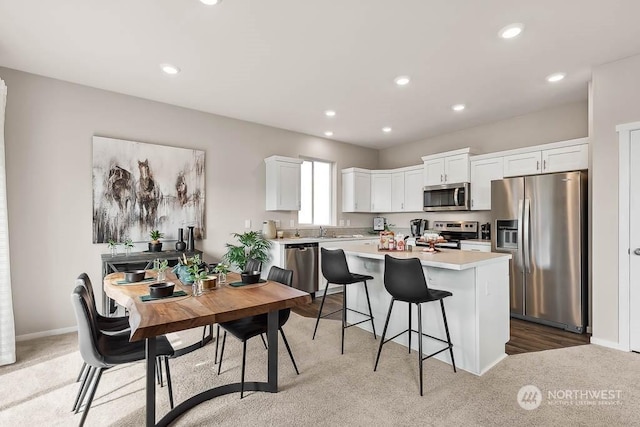 kitchen featuring a breakfast bar, white cabinets, carpet, a center island, and stainless steel appliances