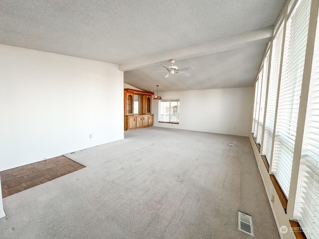 unfurnished living room featuring vaulted ceiling with beams, a textured ceiling, light colored carpet, and ceiling fan