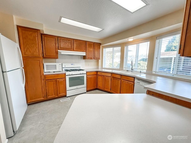 kitchen with tasteful backsplash, white appliances, sink, and a textured ceiling