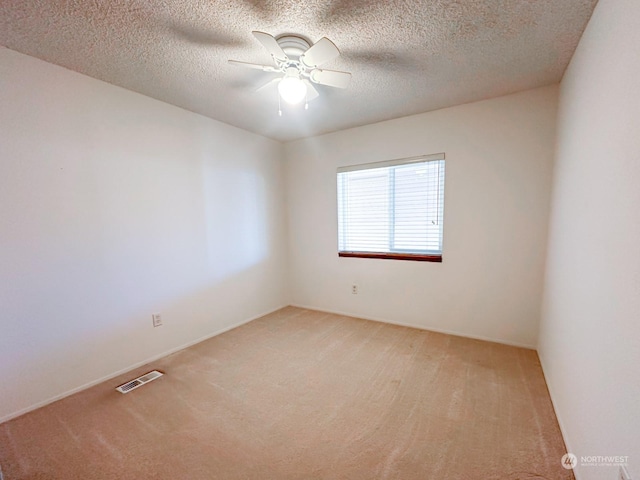 carpeted empty room with ceiling fan and a textured ceiling