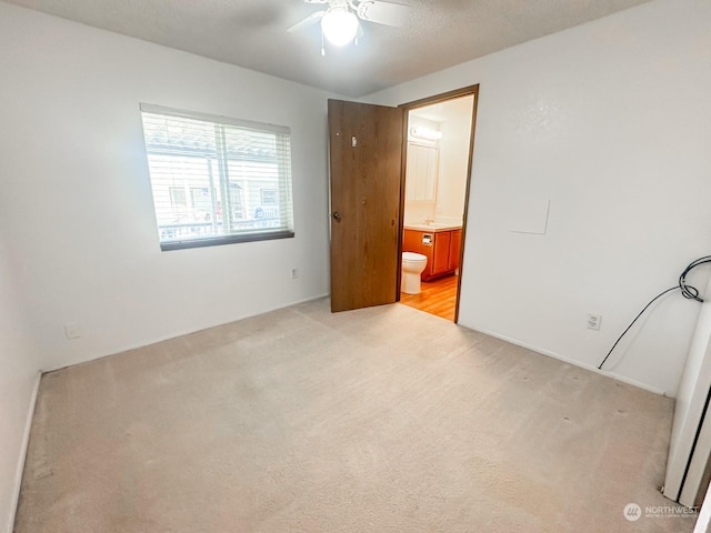 unfurnished bedroom with light carpet, connected bathroom, and ceiling fan