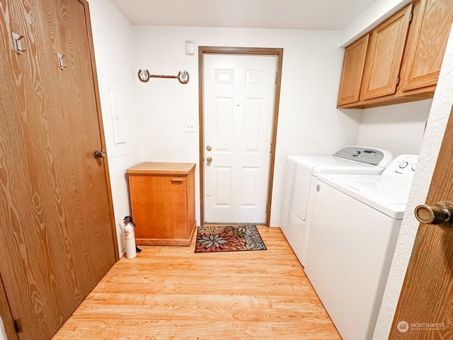 laundry area featuring cabinets, separate washer and dryer, and light hardwood / wood-style floors