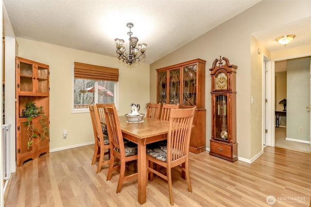 dining space featuring vaulted ceiling, an inviting chandelier, and light hardwood / wood-style floors