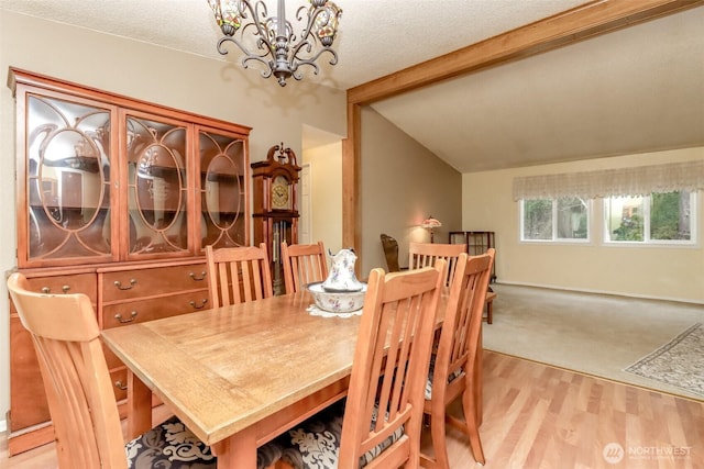 dining area with an inviting chandelier, lofted ceiling with beams, a textured ceiling, and light hardwood / wood-style flooring