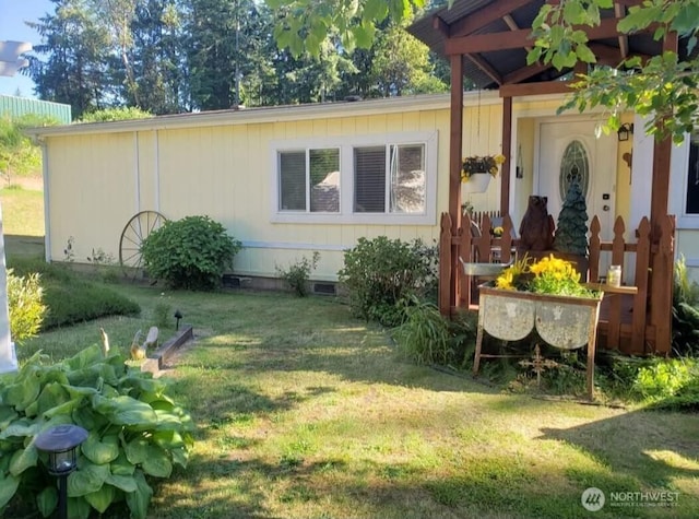 view of side of property with crawl space and a lawn