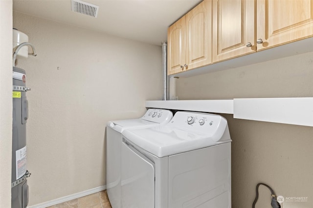 washroom with light tile patterned floors, washing machine and dryer, and cabinets