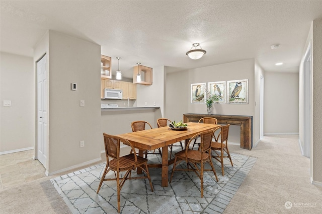 dining space featuring light carpet and a textured ceiling