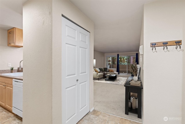 hall with light colored carpet and sink