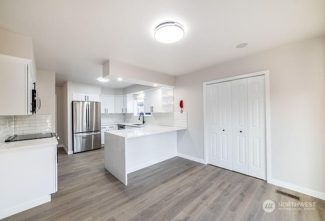 kitchen with sink, appliances with stainless steel finishes, white cabinetry, decorative backsplash, and kitchen peninsula