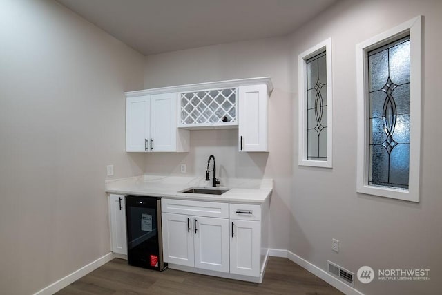 bar with dark hardwood / wood-style flooring, sink, black dishwasher, and white cabinets