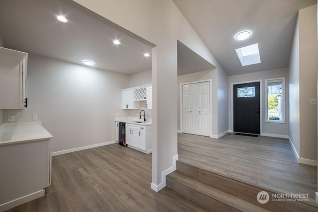 foyer entrance featuring lofted ceiling, sink, and light hardwood / wood-style flooring