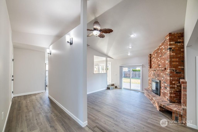 unfurnished living room featuring ceiling fan, lofted ceiling, hardwood / wood-style floors, and a brick fireplace